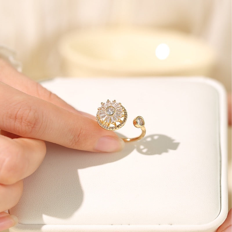 finger holding gold plated fidget ring with zirconia windmill design