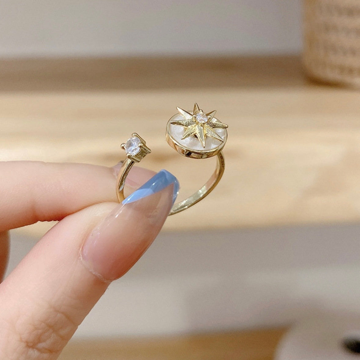 finger holding gold plated ring with pearl star design