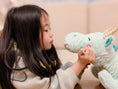 Load image into Gallery viewer, little girl looking her dragon plushie
